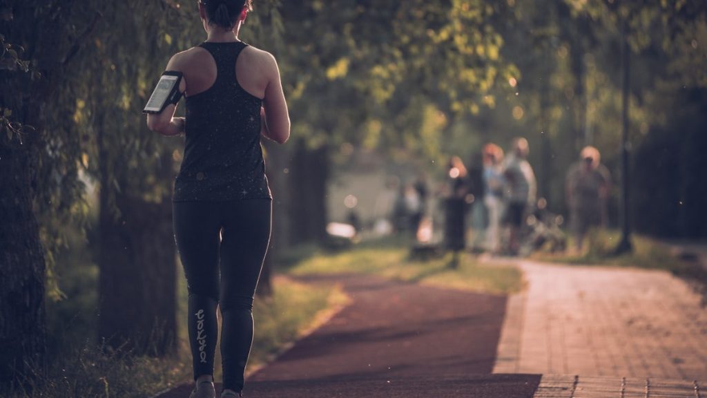 woman in black tank top and black pants walking on sidewalk during daytime